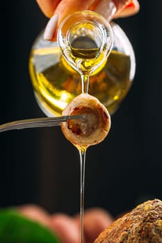 Woman's hand pouring olive oil on mushroom