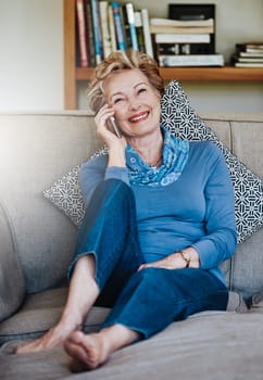 Staying in touch, staying happy. a relaxed senior woman using a phone at home on the sofa.