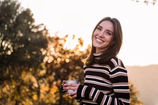 woman smiling with a mug of hot drink in nature