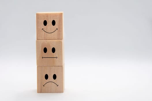 Happy, sad and neutral emoticon faces on stacking wooden cubes with white background cover. Customer satisfaction and evaluation concept.