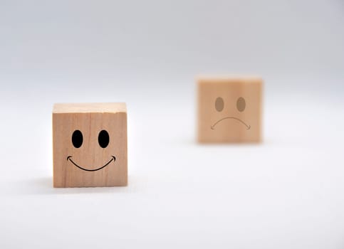 Happy and sad emoticon faces on wooden cubes with white background cover. Customer feedback, satisfaction and evaluation concept