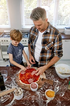 Then you add your meat...a father and his son making pizza at home.