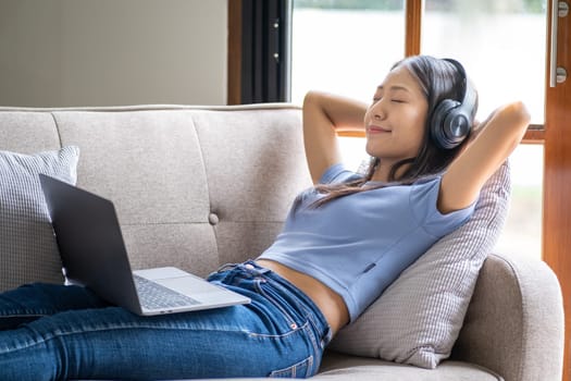 Beautiful young smart teenager woman with headphones relaxing on the bed sofa at home, Happy young teenager Asian listen
