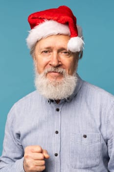 Happy confident cool old bearded Santa Claus winner raising fist celebrating triumph and success over blue background