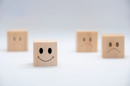 Happy and sad emoticon faces on wooden cubes with white background cover. Customer satisfaction and evaluation concept.