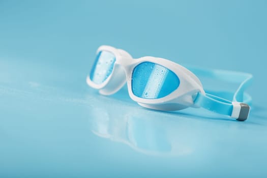Swimming goggles in a white frame with on a blue background