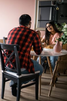 Happy indian couple having breakfast and small talk together in the kitchen - friendship, dating and family
