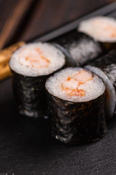 Close up Maki shrimp sushi close-up. Shrimp fillet stuffing wrapped in rice and nori seaweed. Japanese cuisine