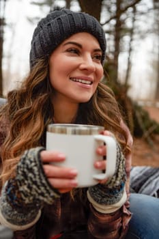 Out for some camping bliss. a young woman drinking a warm beverage while camping in the wilderness during winter.