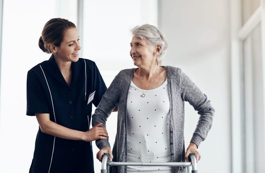 Shes all the care you need. a female nurse assisting a senior woman using a walker.