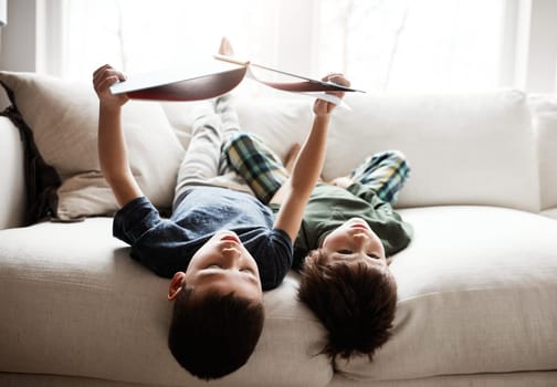 Read together, grow together. two adorable brothers reading books while relaxing together on the sofa at home.