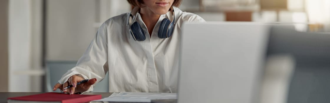 Focused european business woman working laptop and making notes while sitting in modern office