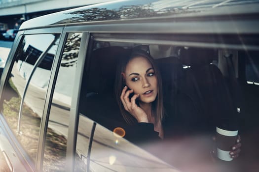 Lets arrange a face to face meeting. a young businesswoman using a mobile phone while traveling in a car.