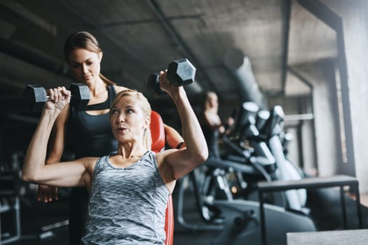 For muscles of steel, add weights. a mature woman lifting weights with a female instructor at the gym.