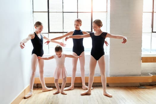 Practice makes every pointe perfect. a group of young ballerinas teaching a little girl ballet in a dance studio.
