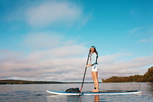 Youll never regret a trip out on the water. a young woman paddle boarding on a lake.