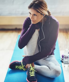 Fitness leads to happiness. an attractive young woman listening to music while working out at home.
