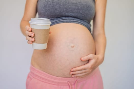 A pregnant woman holds a cup of coffee in her hands. Caffeine safety, myths about coffee during pregnancy concept