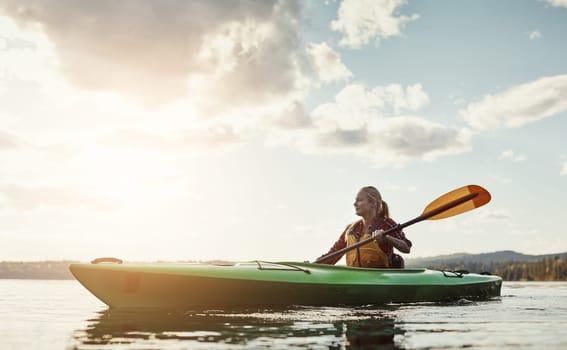 An outdoors activity with a little exercise involved. a young woman kayaking on a lake.
