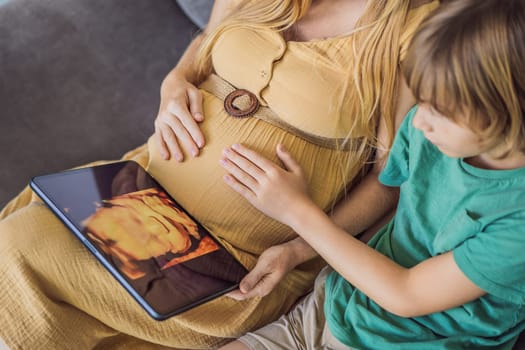 Mom and her son looking on ultrasound image of his unborn baby brother on mothers tablet. Concept of healthcare and family happiness expecting baby