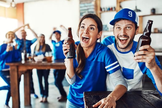 Crack open a cold one and enjoy the game. a young couple having beer while watching the game in a bar.