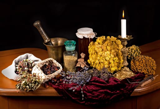 Dried healing herbs, flowers and candles, ritual purification , copyspace Close up of healing herbs alchemist stuff. Old pharmacy, alternative medicine concept. mortar and pestle. on a black background. wooden table.