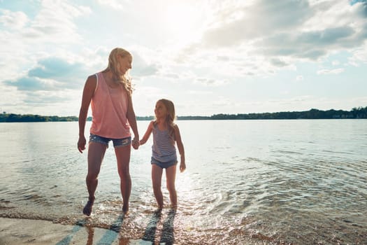 Every memory becomes better once shared with family. mother and daughter playing in the water by a lake outdoors.