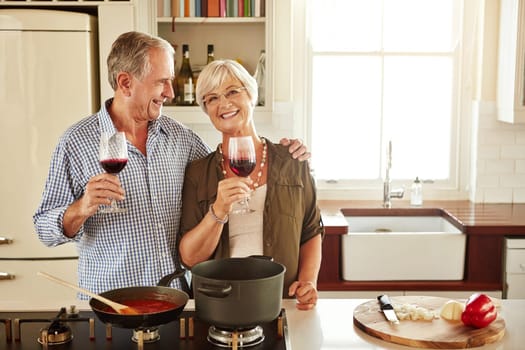 Wine and you, my two favourite things. a senior couple enjoying a glass of wine while cooking supper.