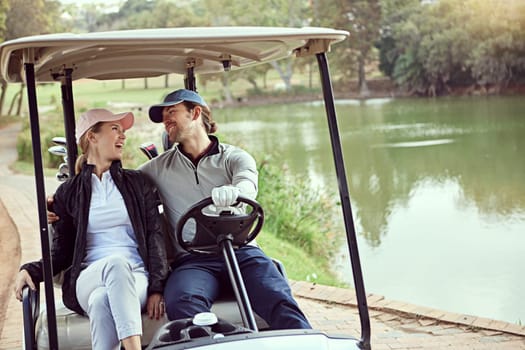 Ready to hit the course. a smiling young couple riding in a cart on a golf course.