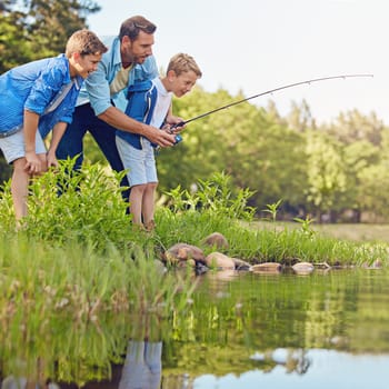 Showing them how to fish. a father and his two sons out fishing in the woods.