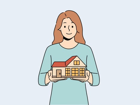 Smiling woman with house model in hands