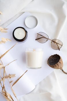 Soy wax aroma candles in brown jar on bed , with fashion glasses. Candle mockup design