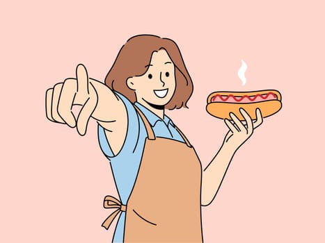 Smiling woman hold hot dog point at screen