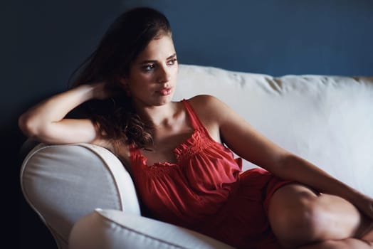 She has a lot on her mind. A beautiful young woman lying on the couch with a thoughtful expression.
