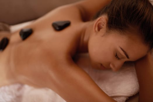 Getting some deep heat. a young woman enjoying hot stone therapy at a spa.