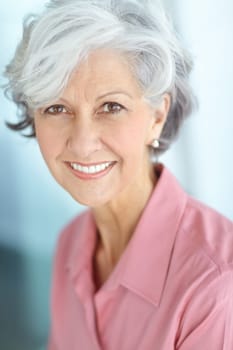 Portrait of one happy senior caucasian woman with grey hair enjoying free time at home. Face of carefree, wise and cheerful retired lady smiling, feeling optimistic about life and ageing gracefully