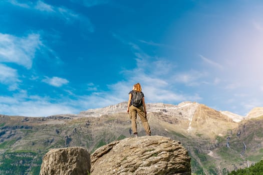 Young Woman With A Backpack on The Top Of a rock in a Beautiful wild Landscape. Discovery Travel Destination Concept