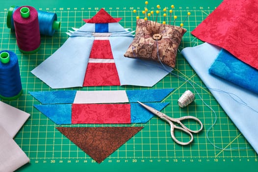 Sewing patchwork of block of lighthouse surrounded by accessories