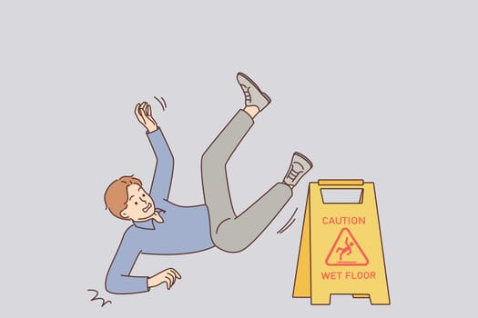 Man falls near warning sign with words caution wet floor due to negligence and inattention