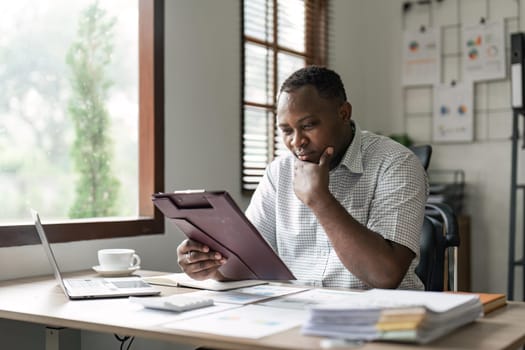 Black business man doing paperwork at home workplace. Entrepreneur reading financial reports, reading documents. Tenant making payment for rent, reviewing bills, bank mortgage notice