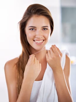 She knows the importance of flossing. Portrait of an attractive young woman holding dental floss and smiling.