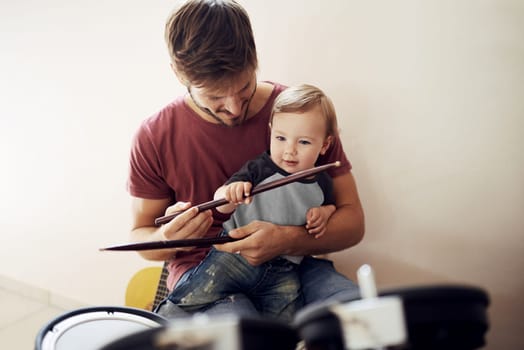 Making a future rockstar. A handsome young father teaching his young son to drum.
