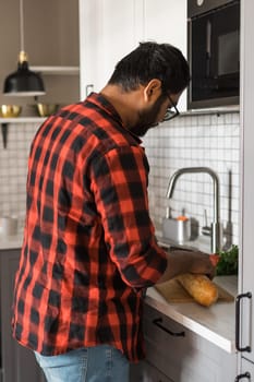 Indian or latino man cooking breakfast while standing at the kitchen at home, rear view