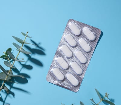 Oval white pills in a gray blister pack on a blue background