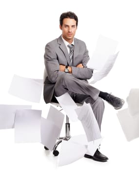 Composure in the corporate storm. A calm businessman sitting amidst a swarm of paperwork.