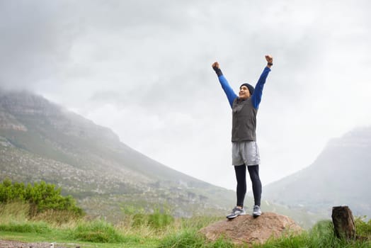 Feeling fit and free. A young man celebrating at the top of a mountain after reachin.