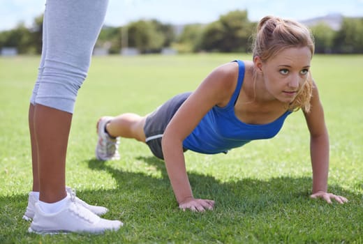 Focused on the next pushup. a woman doing push ups at an outdoors excercise class.