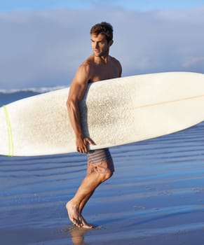 Chasing waves is his passion. A handsome young surfer at the beach craving a good wave.