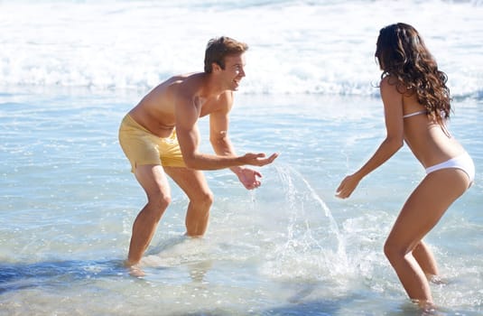 Having fun in the sun. A couple on the beach being playful with the sea water.