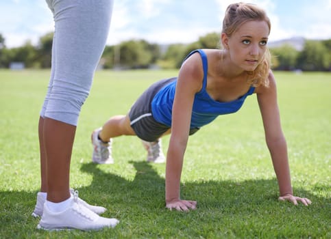 Focused on the next pushup. a woman doing push ups at an outdoors excercise class.